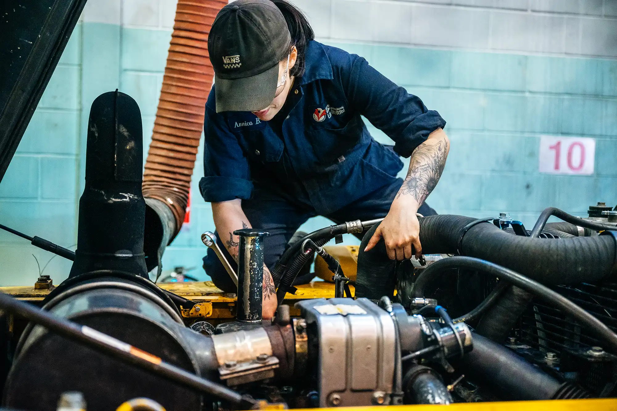 Une élève en mécanique d'engins de chantier inspecte un moteur.